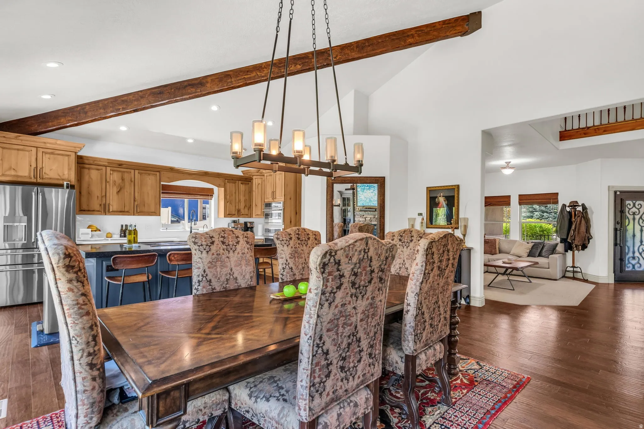 Open-concept dining area featuring wood-finish flooring, a linear chandelier, and exposed wood beams