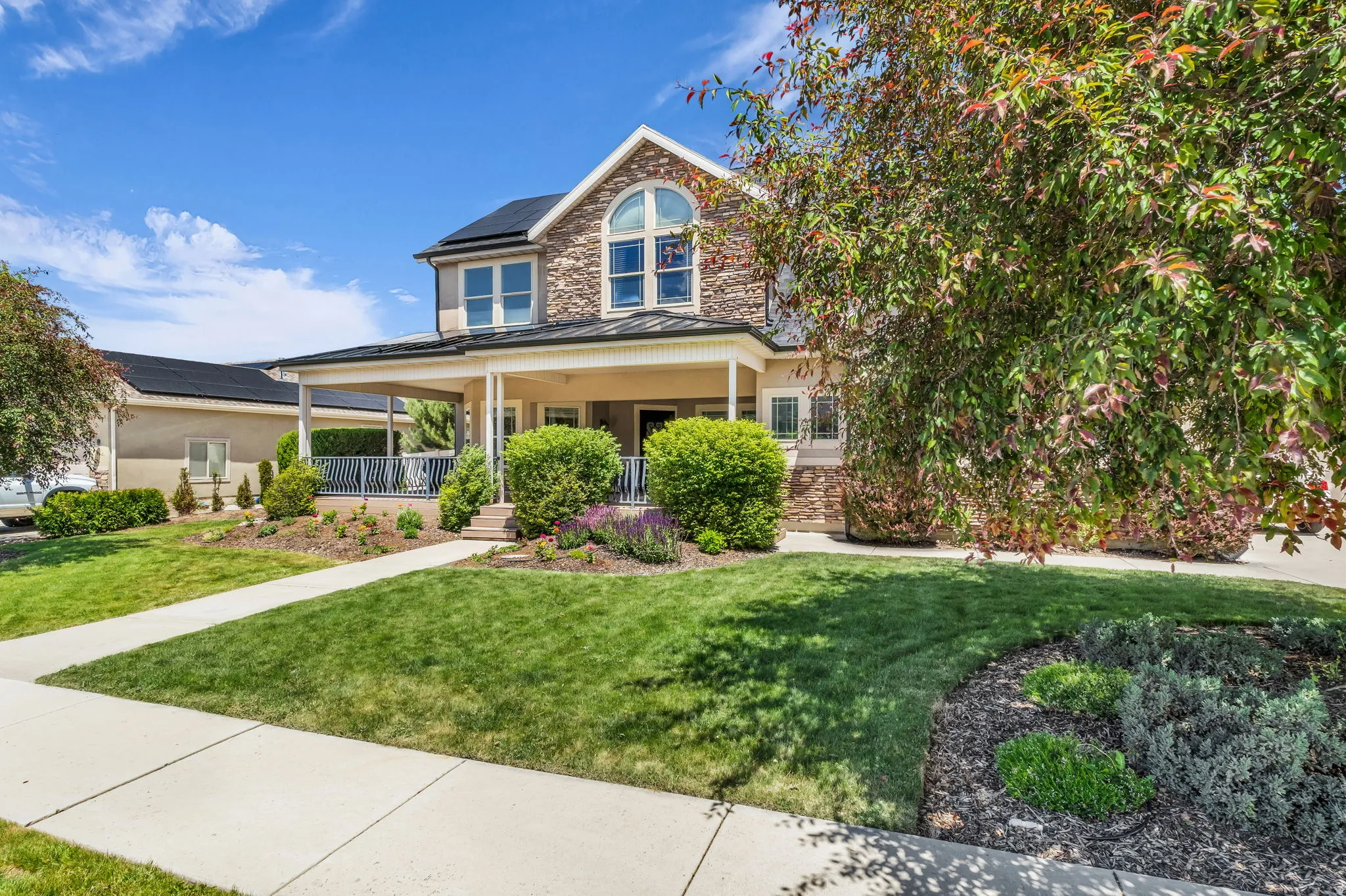 Stone and siding exterior with a covered front porch featuring white columns and dark railing
