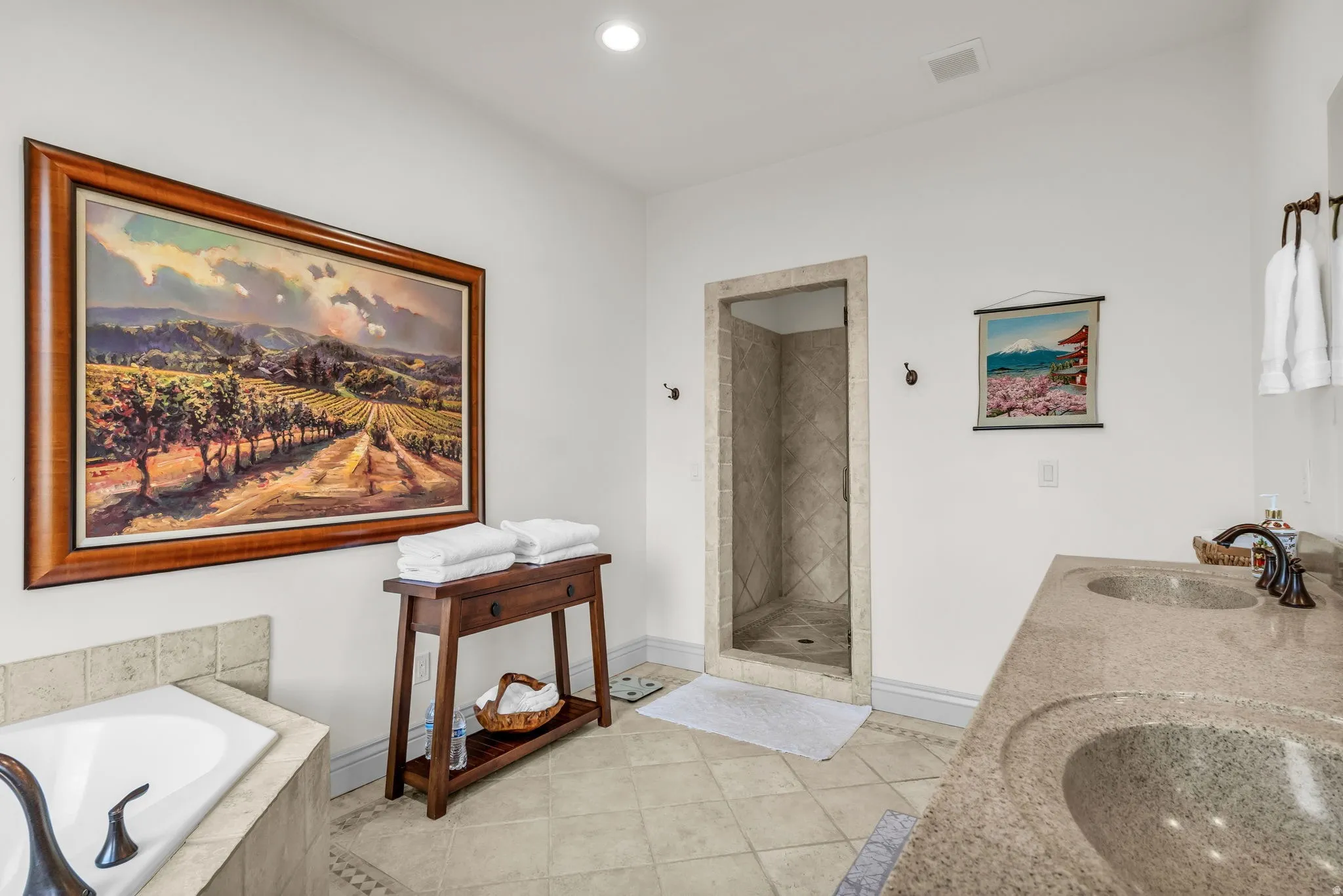 En suite spacious bathroom featuring a dual vanity with integrated sinks, a walk-in shower with tiled surround, a built-in soaking tub, and tile flooring
