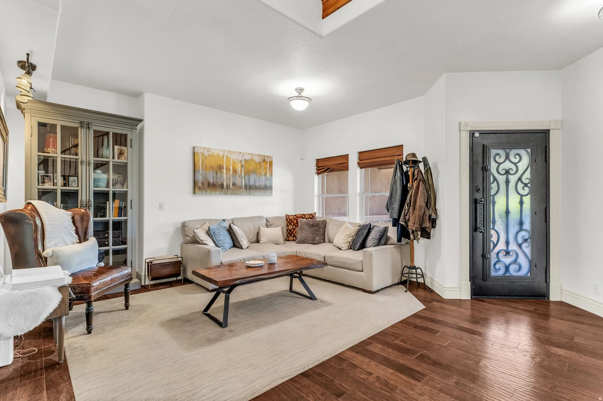 Living area featuring dark wood-finish flooring, white walls, and an ornate wrought iron entry door