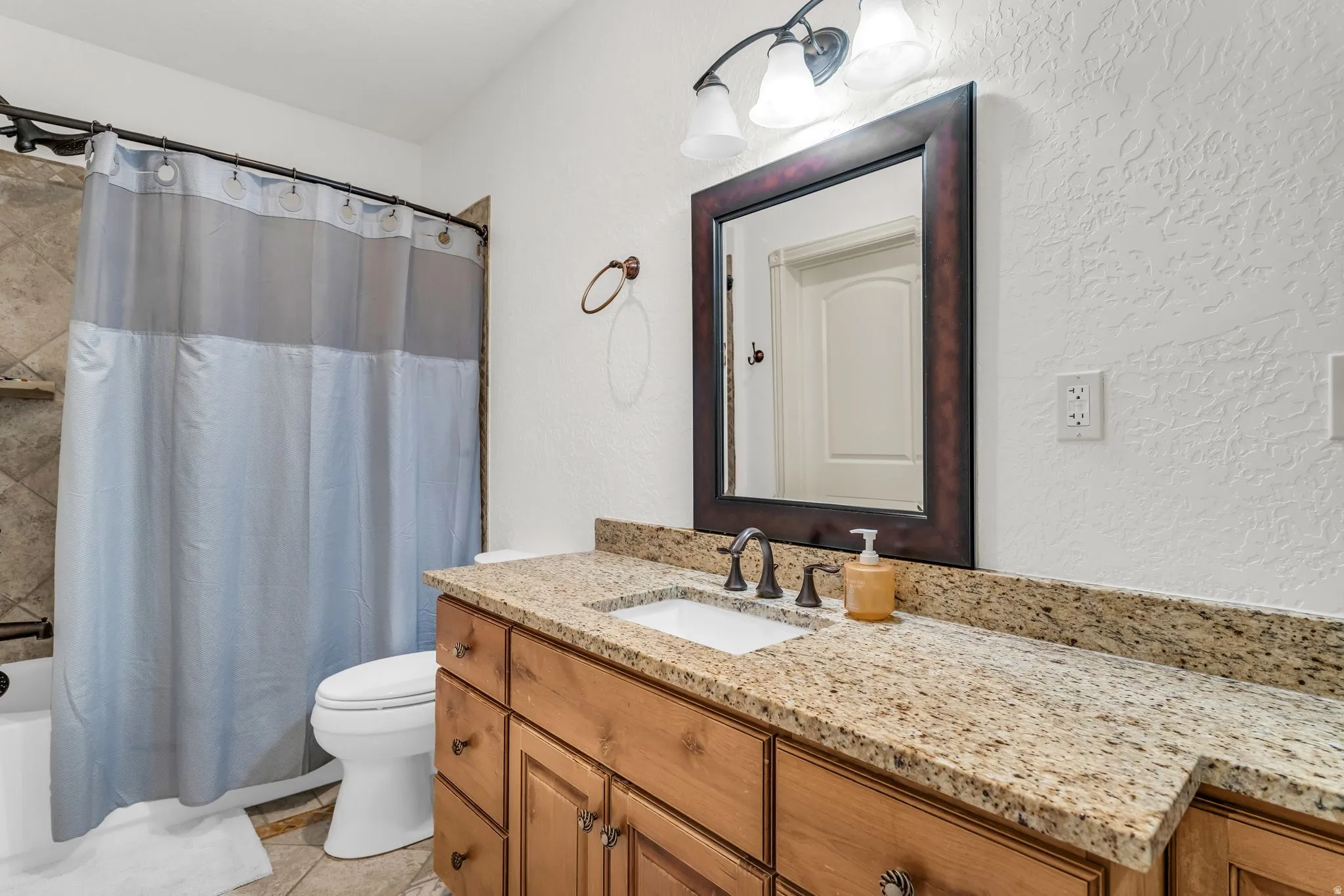 Bathroom vanity featuring an integrated sink, granite-style countertop, and wood-finish cabinetry