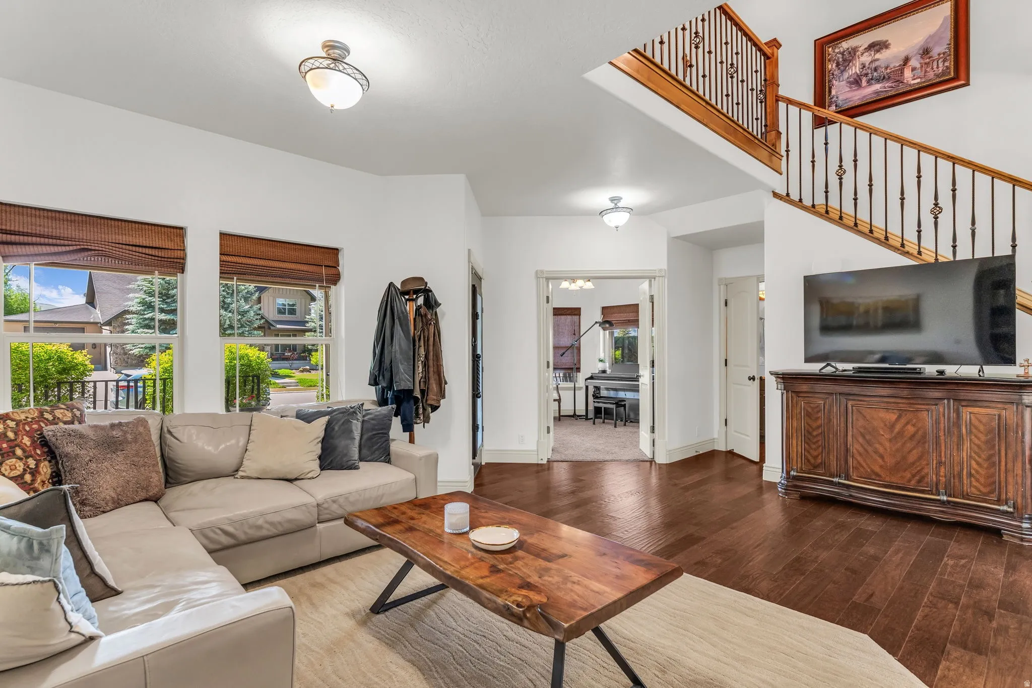 Living area featuring rich wood-finish flooring, white walls, and bright windows