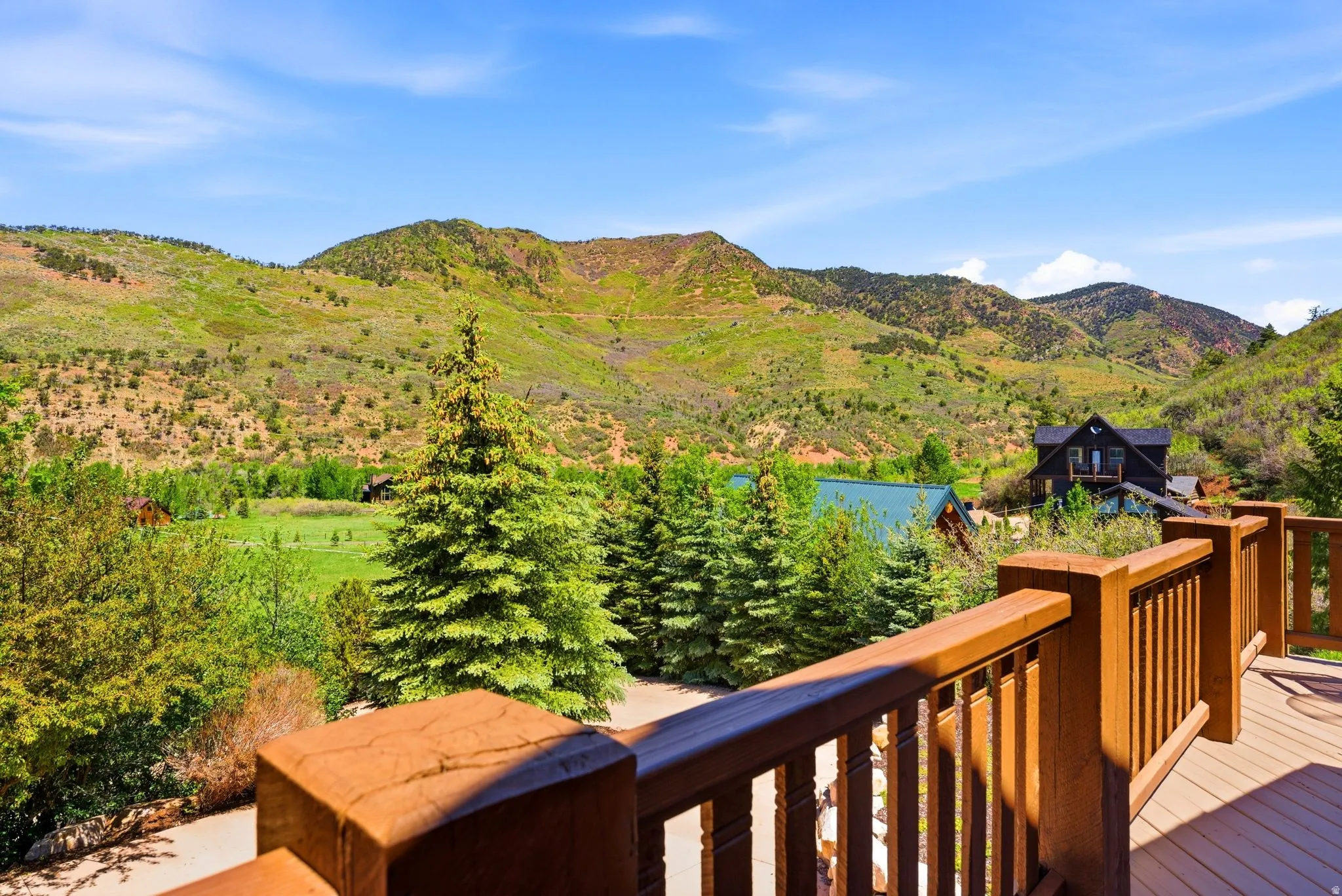 Expansive outdoor deck with natural wood railing and decking, offering panoramic mountain scenery and lush green landscape