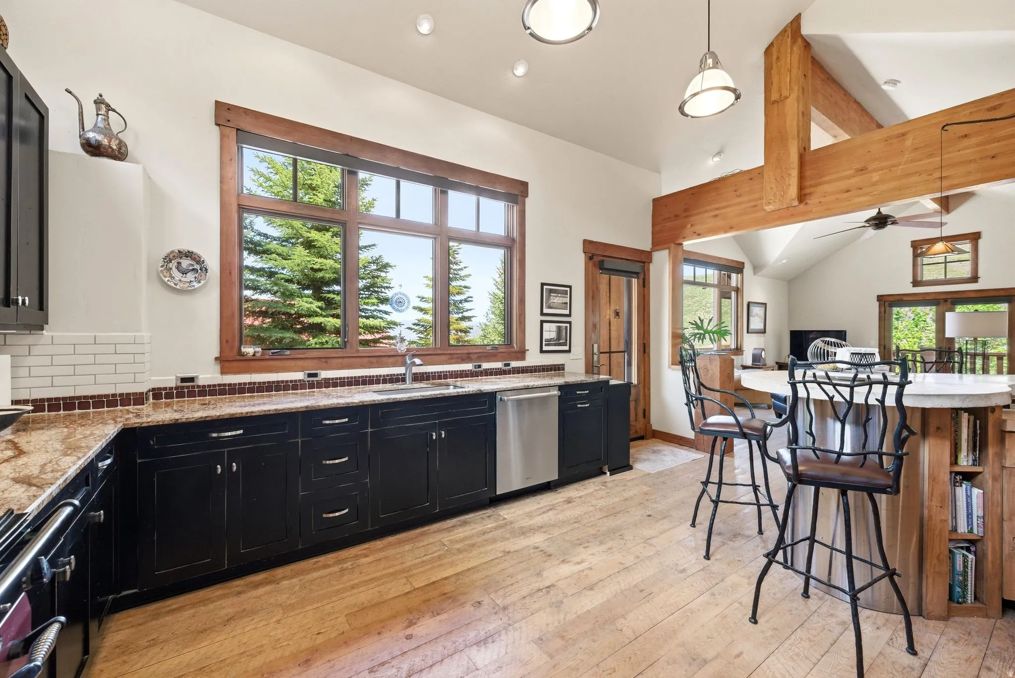 Gourmet kitchen featuring black cabinetry, light granite countertops, and white subway tile backsplash