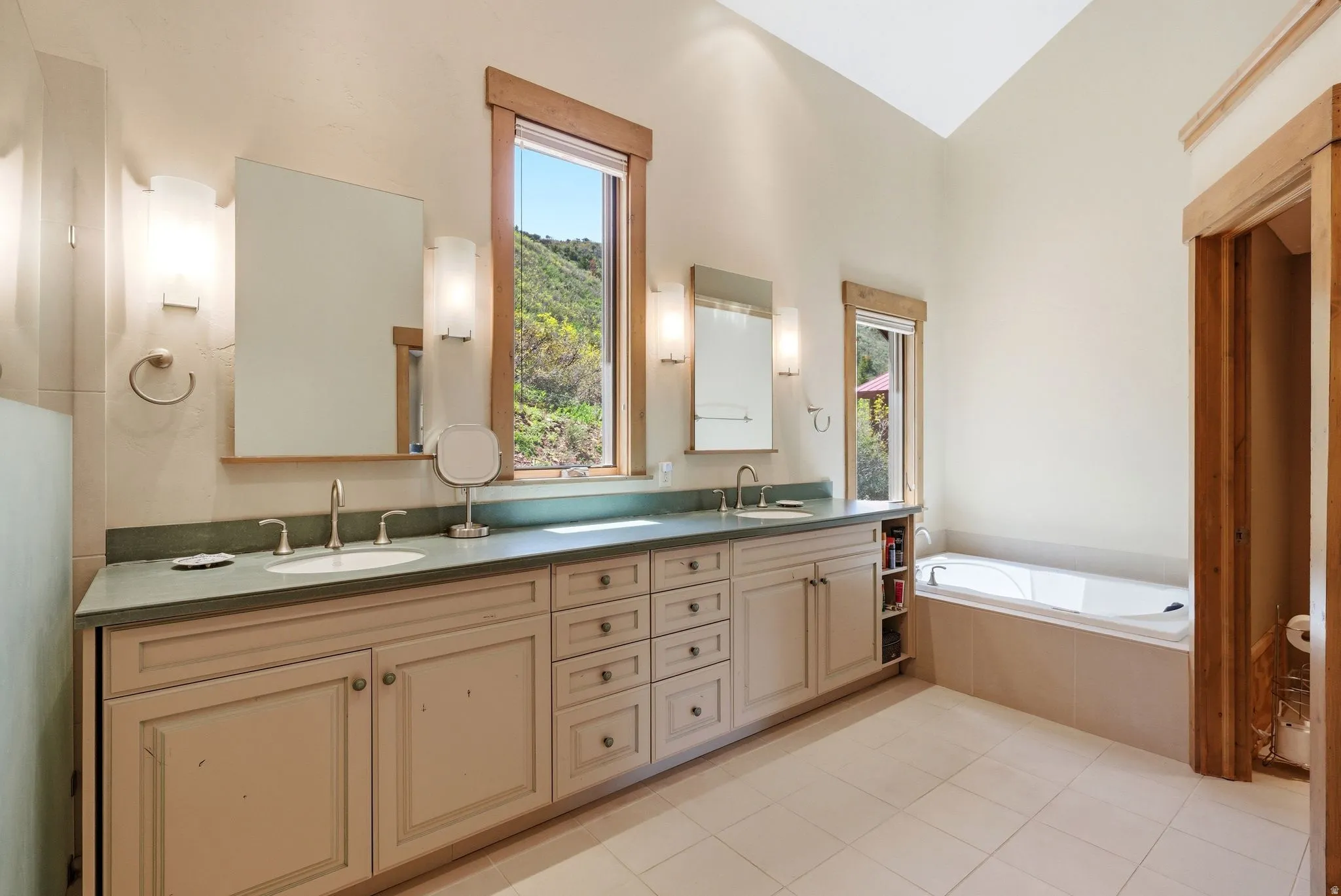 Bathroom featuring a built-in soaking tub, dual vanity with undermount sinks, and two framed mirrors