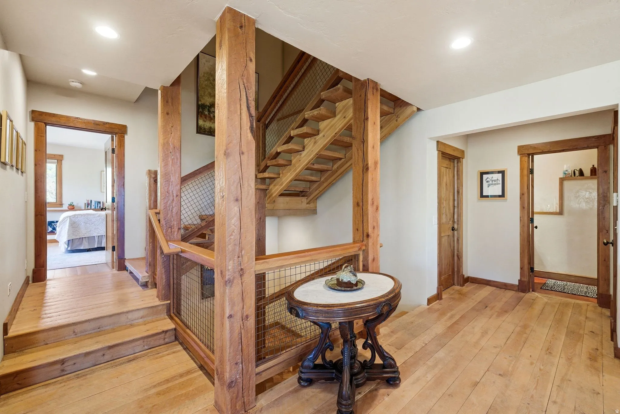 Wood-finish flooring throughout, featuring a natural wood staircase with metal mesh railing