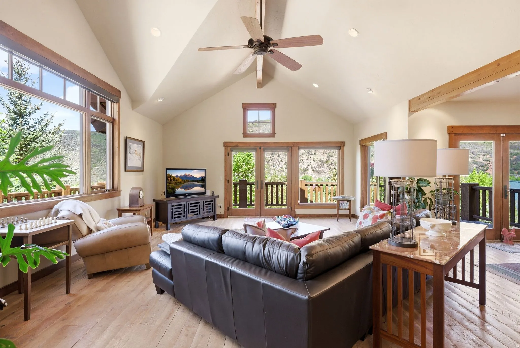 Living area featuring vaulted ceilings with exposed beams, wood-finish flooring, and recessed lighting