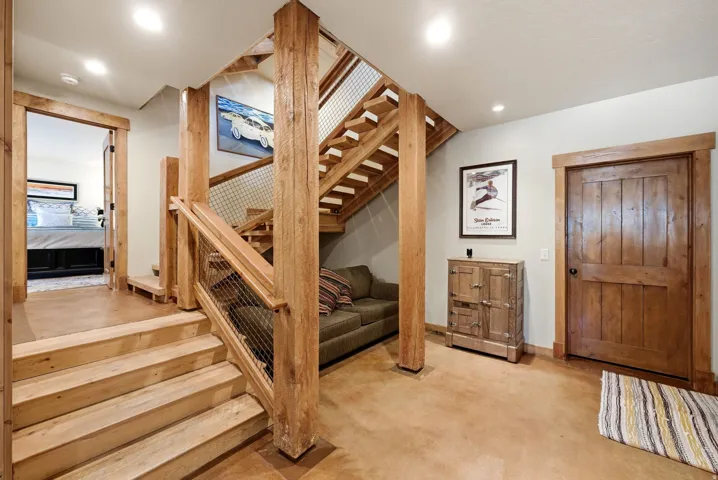 Wood-finish staircase with metal mesh railing and solid wood newel posts