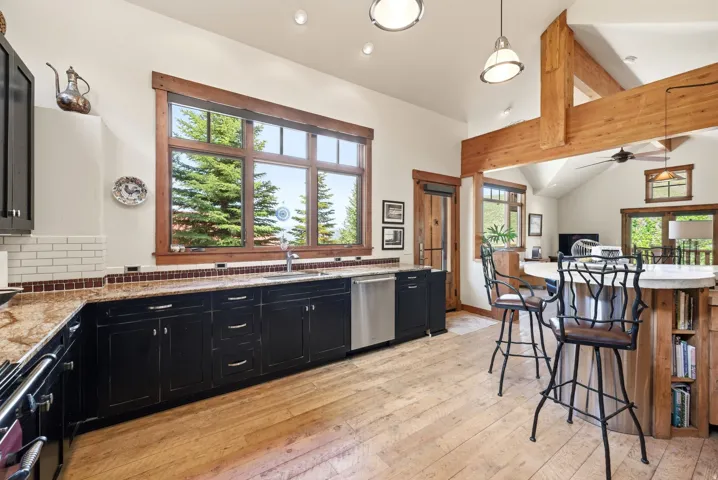 Gourmet kitchen featuring black cabinetry, light granite countertops, and white subway tile backsplash