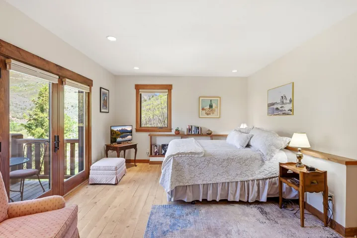 Spacious room featuring wood-finish flooring, recessed lighting, and a private balcony with double glass doors