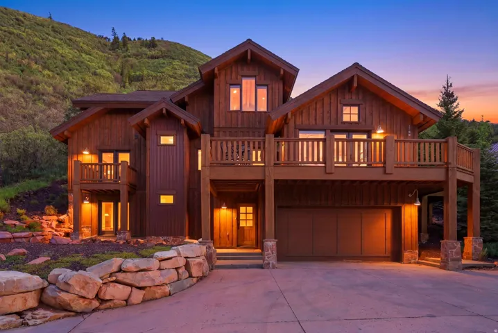 Multi-level wood-clad residence featuring multiple balconies with wood railings, a multi-car garage, and stone accent pillars
