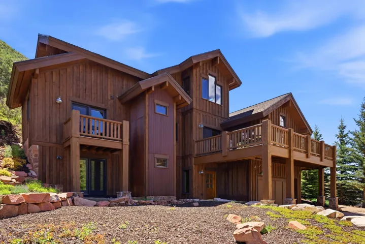 Multi-level residential exterior featuring warm wood siding, a prominent gabled roofline, and multiple outdoor deck spaces