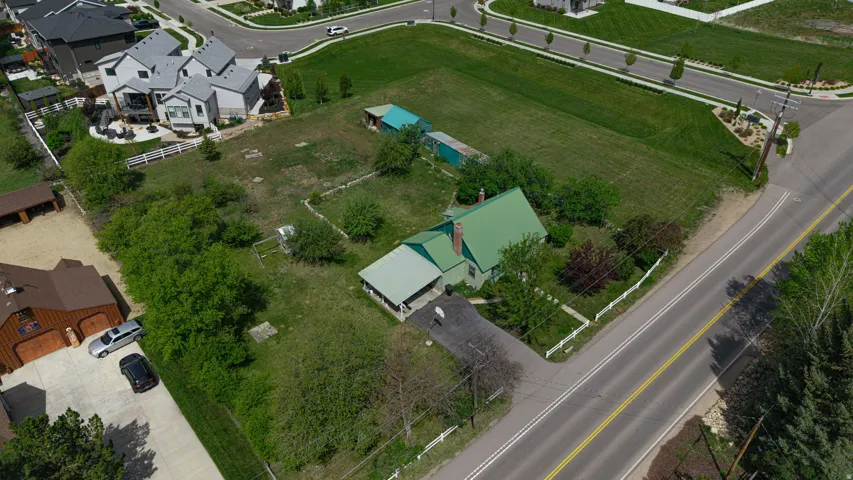 Expansive property featuring a green-roofed residence, extensive grassy areas, and mature trees