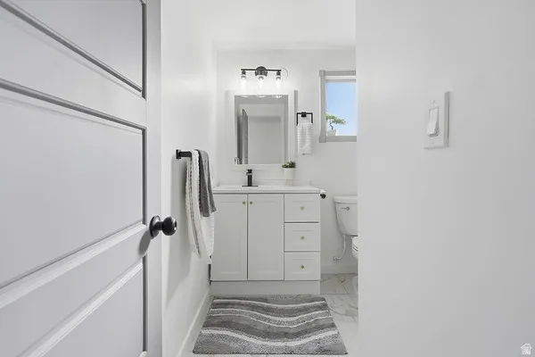 Bright bathroom featuring a white vanity with gold-tone hardware, a black-framed mirror, and a contemporary three-light fixture