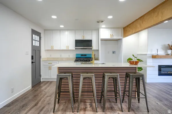 Kitchen featuring white cabinetry, gold-finish hardware, light wood-finish flooring, and recessed lighting