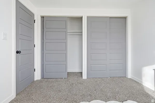 Gray five-panel interior door with black hardware, complementing gray two-panel sliding closet doors, and textured gray carpet