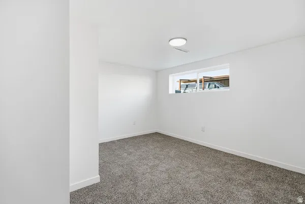 Carpeted room featuring white walls, a single horizontal window, and a flush-mount ceiling light fixture