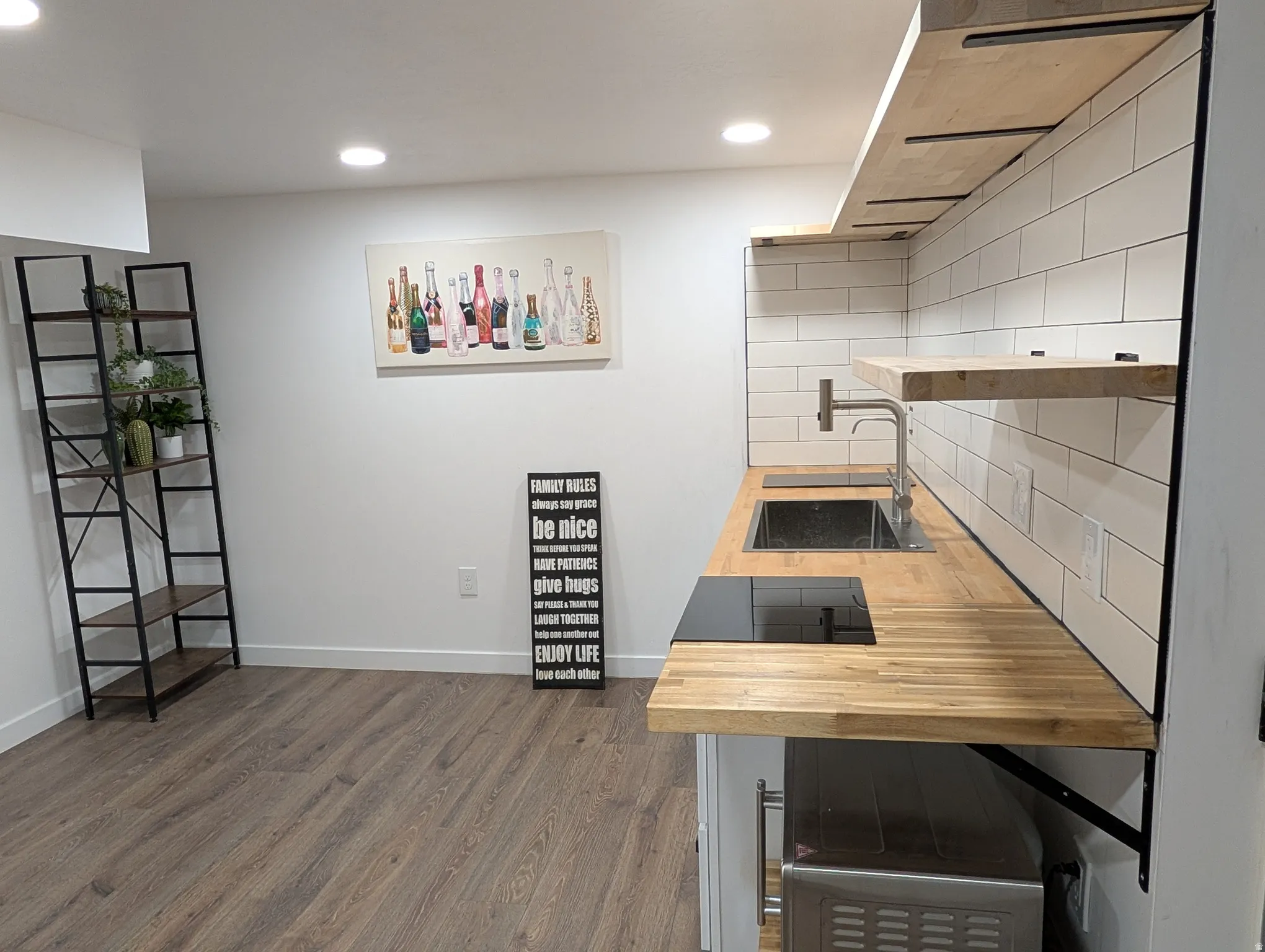 Compact kitchen area featuring wood-finish countertops, subway tile backsplash, and an integrated cooktop