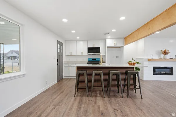 Open-concept living space featuring wood-finish flooring, recessed lighting, and a white color palette
