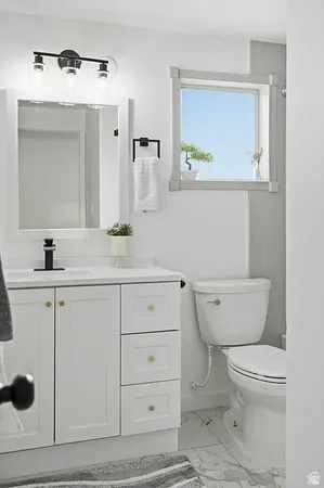 Bathroom vanity with white cabinetry, gold-finish hardware, and a white countertop