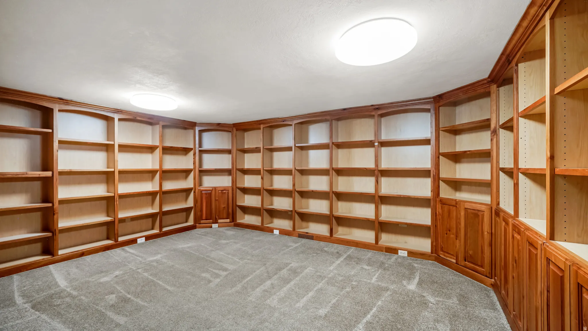 Room featuring extensive built-in wood shelving, integrated cabinetry, and carpet flooring