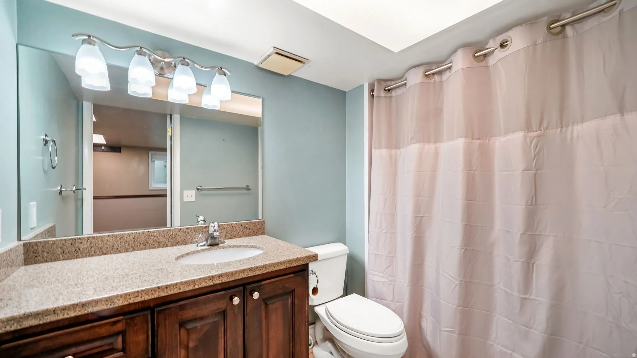 Bathroom featuring a dark wood vanity with a speckled countertop and an undermount sink
