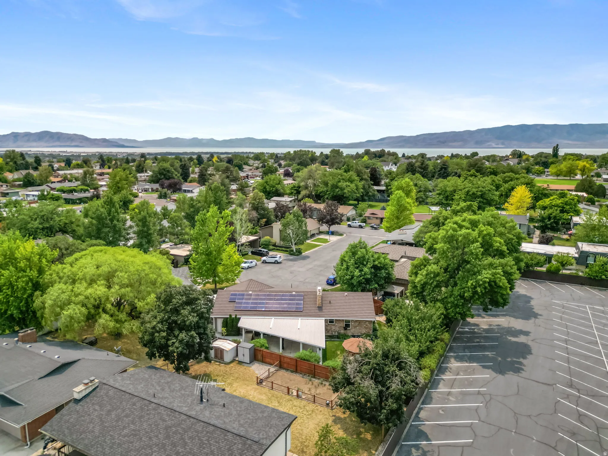 Single-story residence featuring solar panels, a brown shingle roof, and a private wooden fence