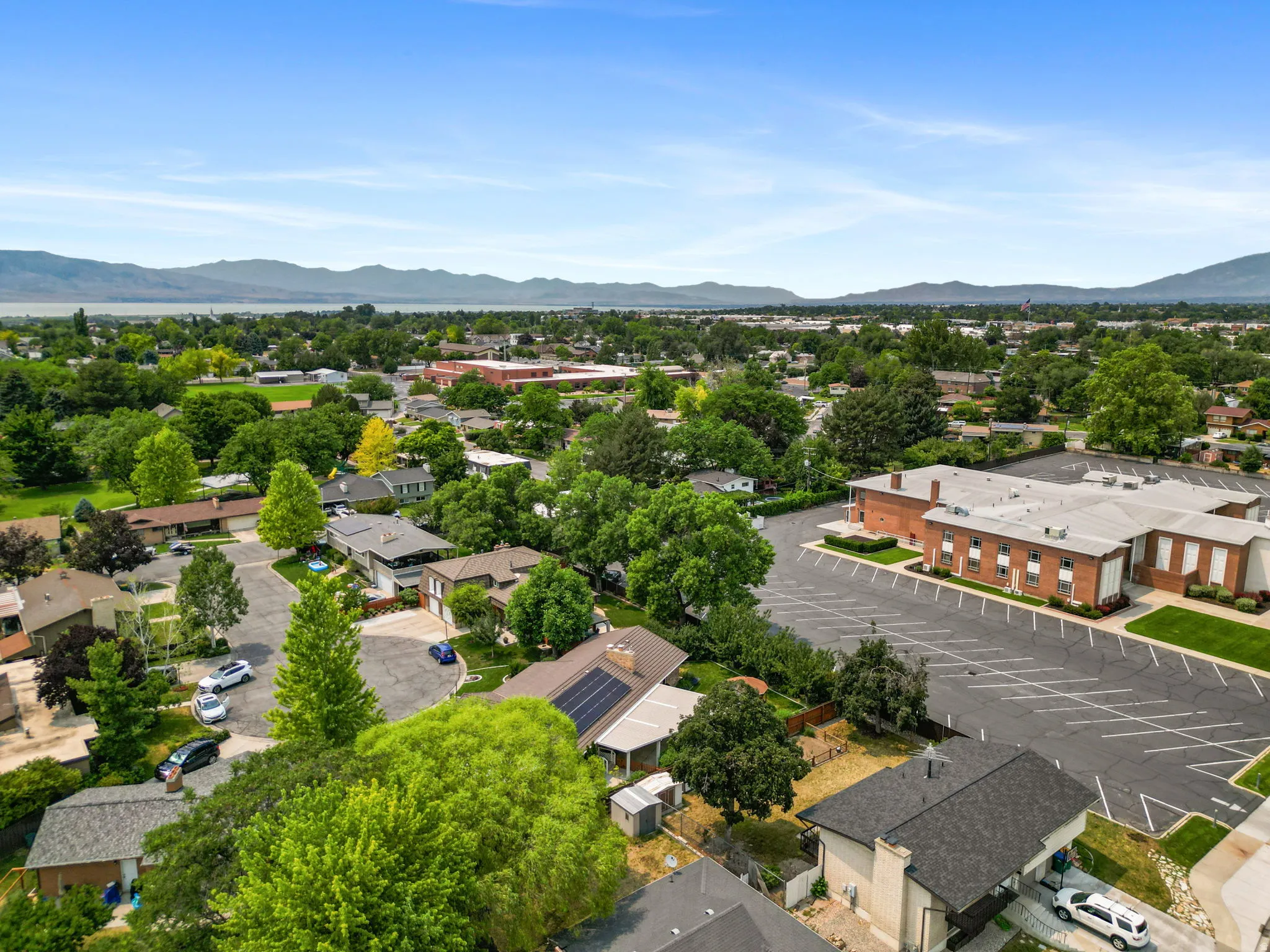 Aerial perspective showcasing a residential area with mature trees and mountain scenery