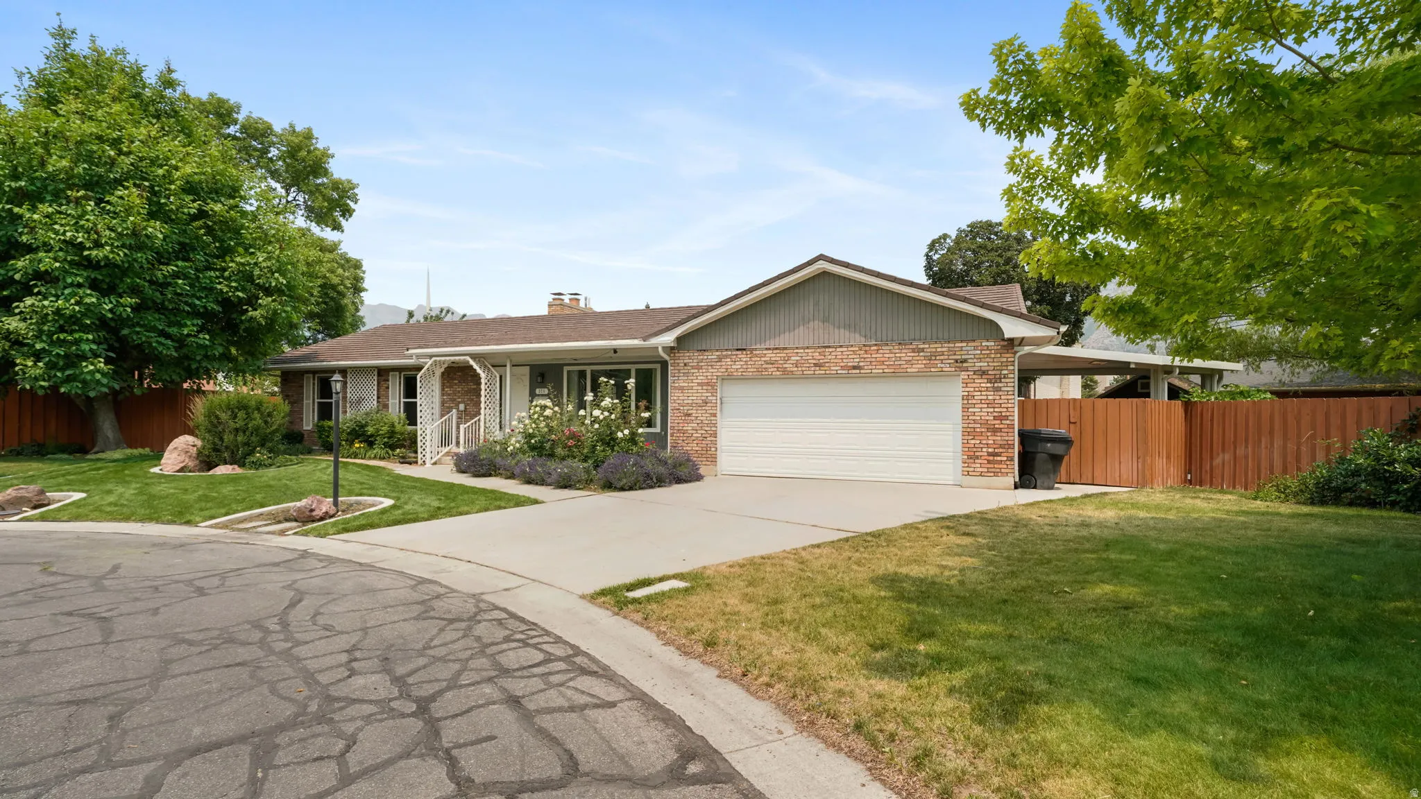 Ranch-style residence featuring a brick facade, attached garage, and a concrete driveway