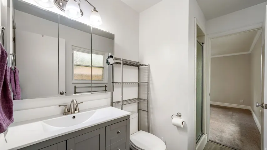 Bathroom featuring a gray vanity with an integrated white sink, brushed nickel faucet, and overhead lighting fixture