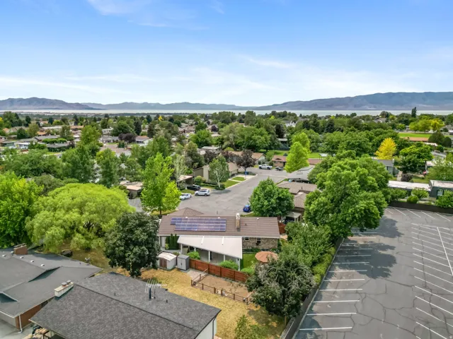 Single-story residence featuring solar panels, a brown shingle roof, and a private wooden fence