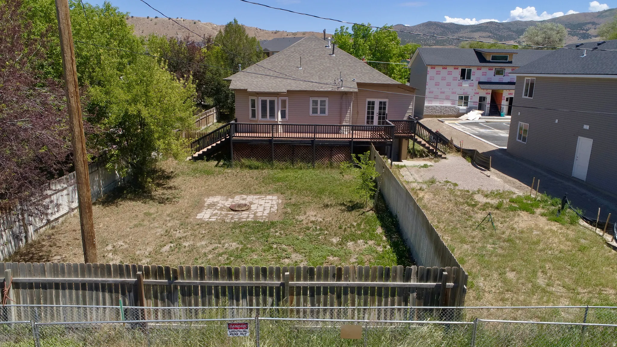 Spacious backyard featuring a brick patio area, wood fencing, mature trees, and a multi-level wood deck with stairs