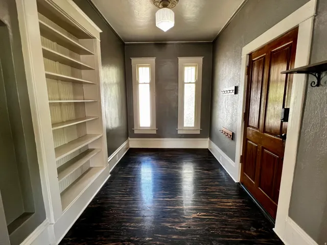 Entryway featuring dark wood-finish flooring, built-in shelving, and a paneled wood door