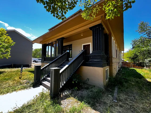 Traditional architectural style featuring a prominent covered porch with substantial dark columns and railing
