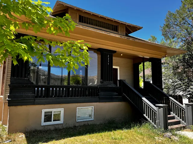 Craftsman-style exterior featuring a broad front porch, dark-painted railing, and decorative columns