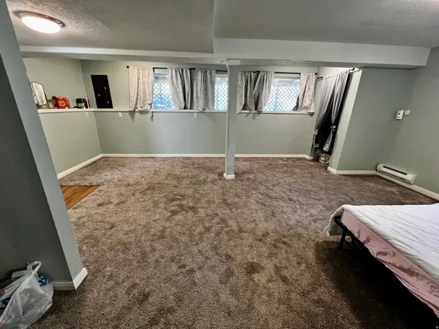 Spacious room featuring broadloom carpeting, light green wall paint, and white trim