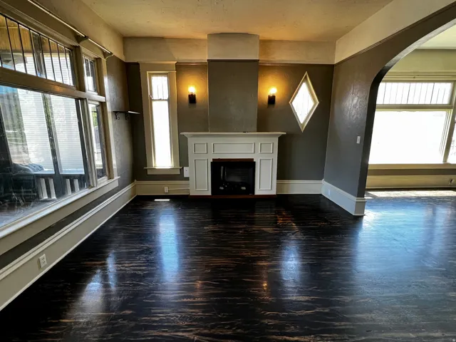 Spacious interior featuring dark wood-finish flooring and a white-mantled fireplace