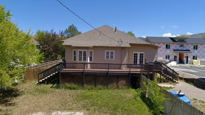Rear exterior of a single-story residence featuring a large wooden deck with dark railings and lattice skirting