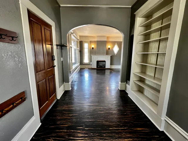 Dark wood-finish flooring extending through an arched entryway