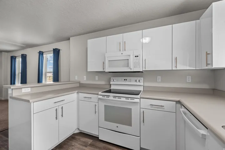 Contemporary kitchen featuring white cabinetry with brushed nickel hardware, laminate countertops, a white electric range, and an over-the-range microwave