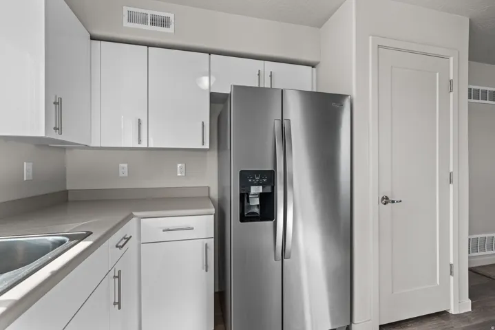 Bright kitchen featuring white cabinetry with brushed nickel hardware, light-toned countertops, and a built-in stainless steel refrigerator with an ice and water dispenser