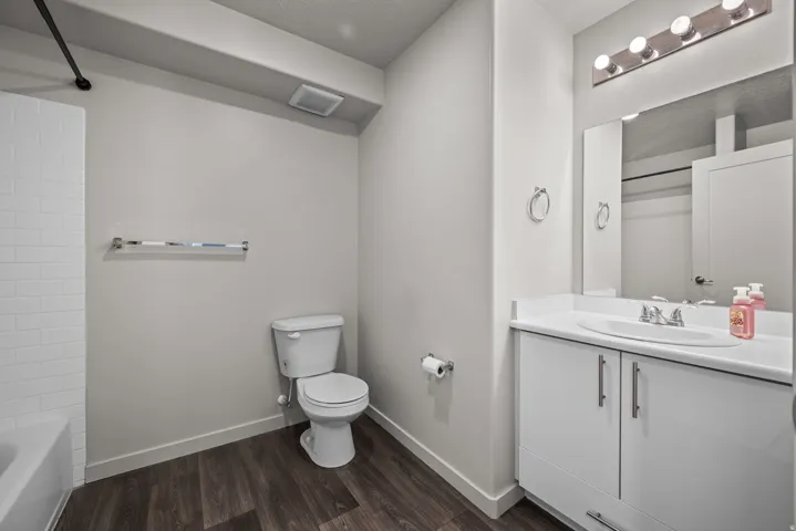 Bathroom featuring a white vanity with integrated sink, a rectangular wall-mounted mirror, and a five-bulb vanity light fixture