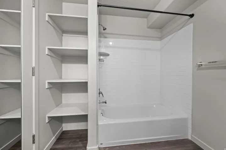 Bathtub and shower combination featuring white subway tile surround, chrome fixtures, and a black shower rod