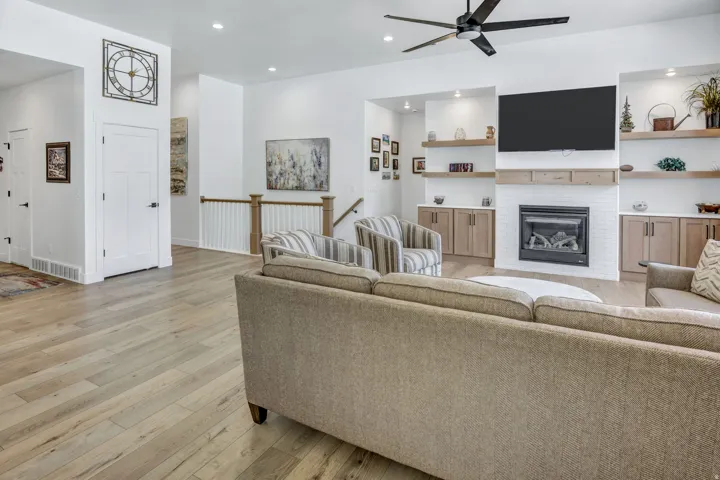 Spacious living area featuring light LVP flooring, a contemporary ceiling fan, and recessed lighting