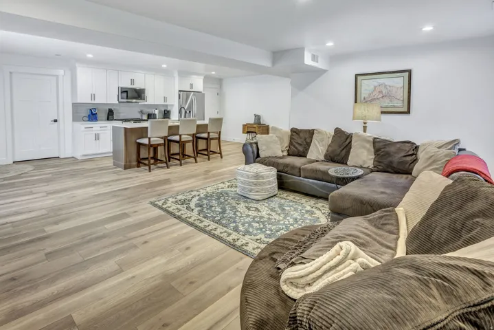Open-concept living area featuring LVP flooring, recessed lighting, and a white kitchen with an island and stainless steel appliances