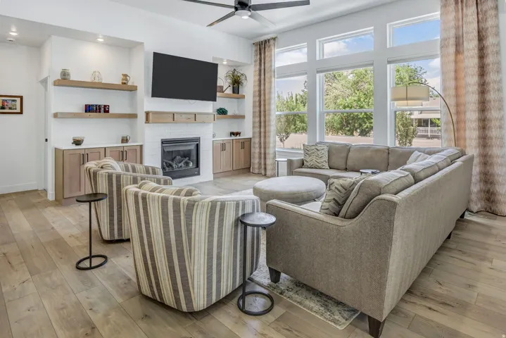 Living space featuring LVP flooring, a white tiled fireplace, built-in cabinetry, floating wood shelves, and large pane windows