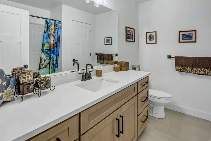 Bathroom featuring a light wood-finish vanity with ample storage, a clean white countertop, and a single undermount sink