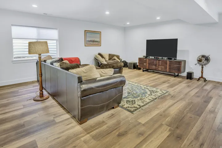 Spacious living area featuring LVP flooring, recessed lighting, white walls, and a window with horizontal blinds