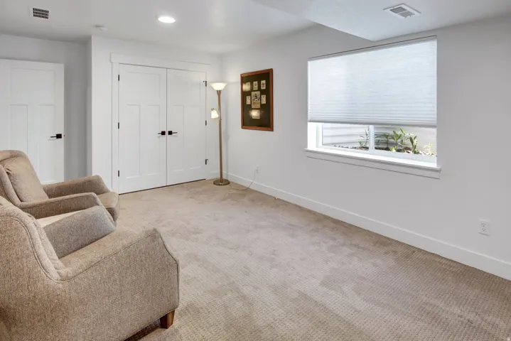Neutral-toned carpeting extends throughout this interior space, featuring a window with a cellular shade