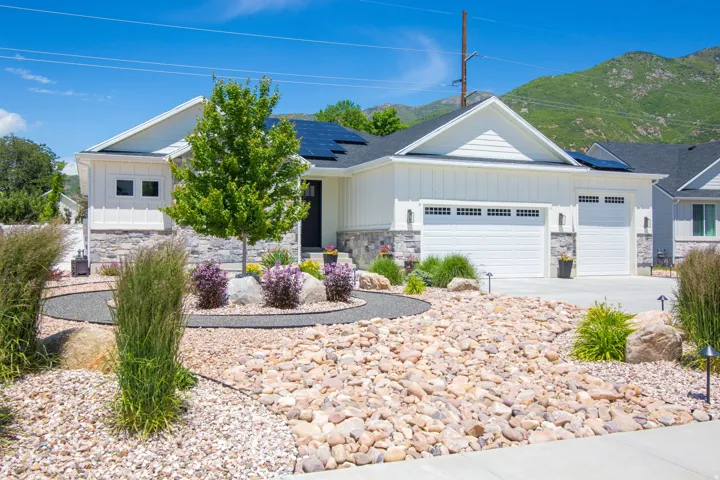 Modern ranch-style exterior featuring white vertical siding and stone veneer accents